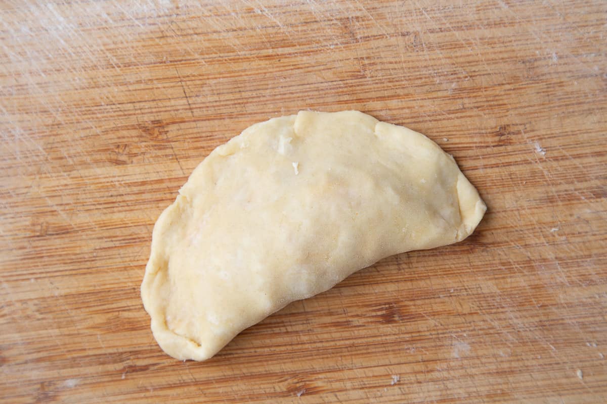 sealed empanada on a cutting board.