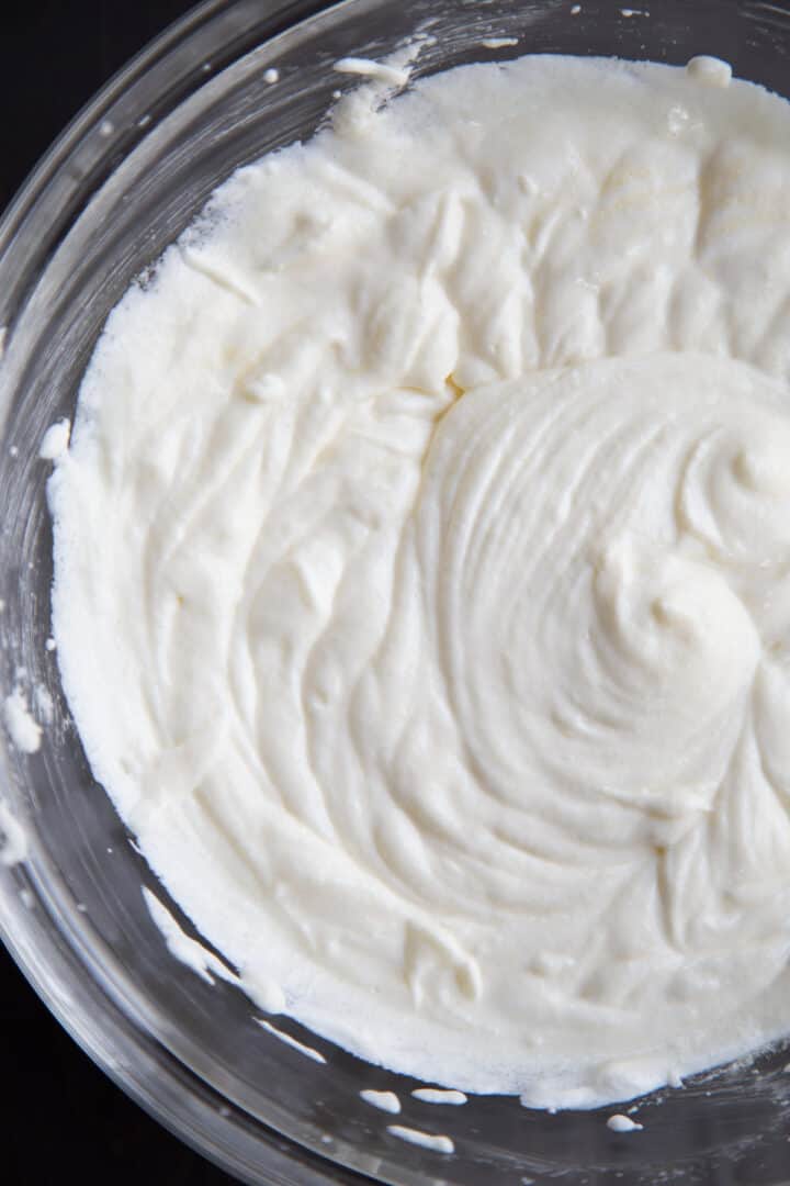 sour cream mixed with butter and eggs in a glass bowl.