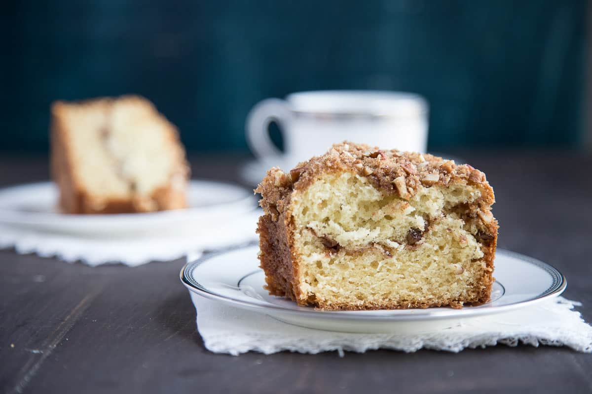 slice of sour cream coffee cake on a white plate with a white napkin.