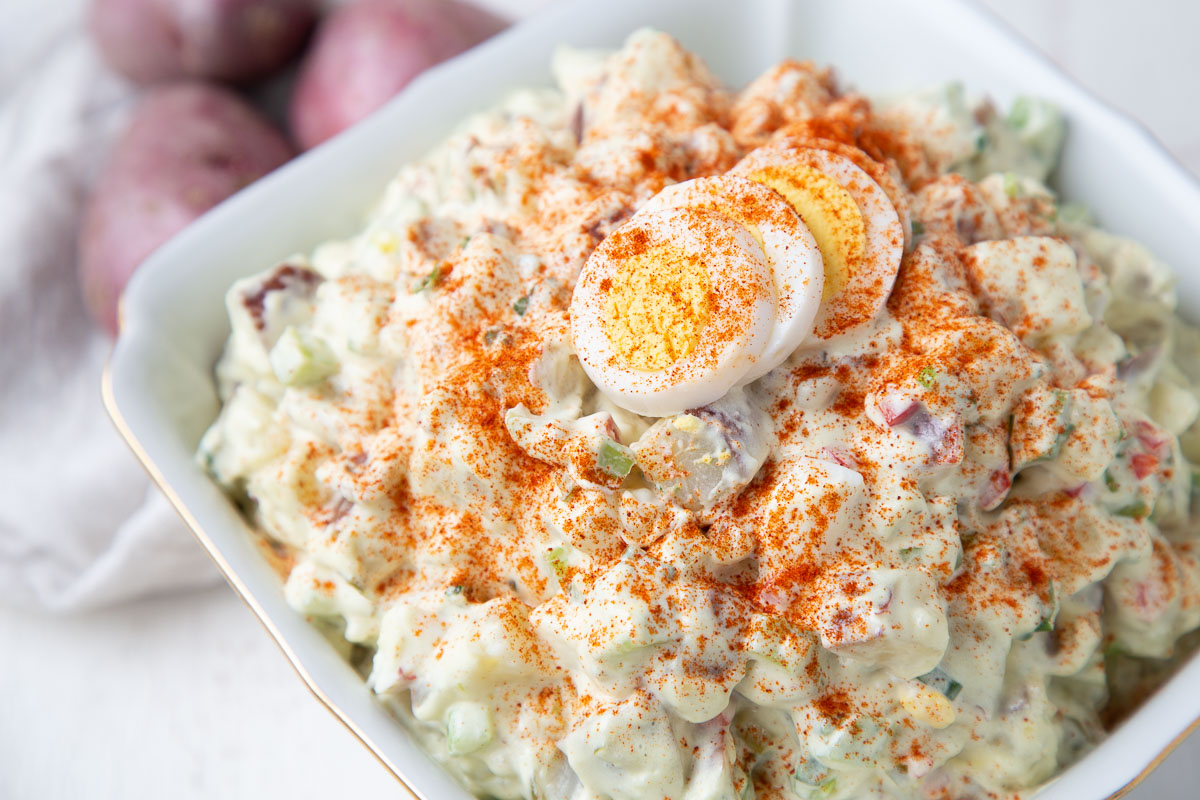 red potato salad topped with paprika and hard boiled eggs.