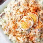 red potato salad topped with hard boiled eggs and paprika.