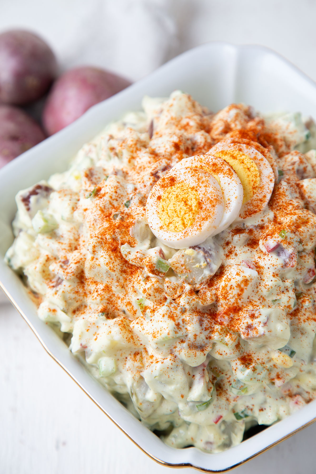 red potato salad topped with hard boiled eggs and paprika.
