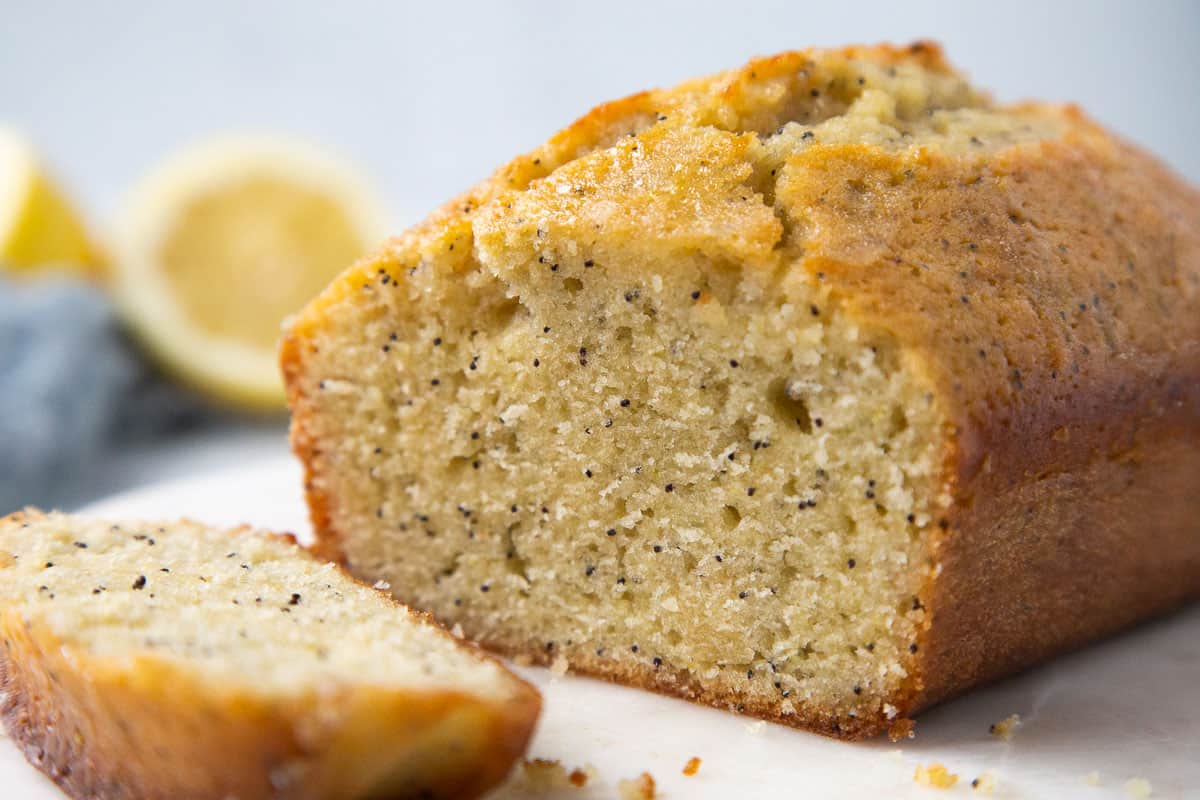 loaf of lemon poppy seed bread with a slice cut out. 