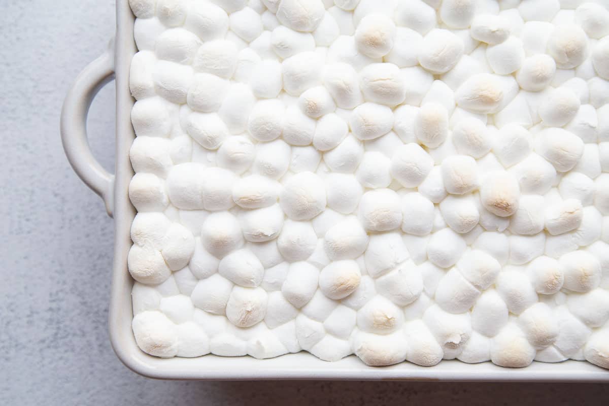 lightly toasted marshmallows on top of cake in a white casserole dish.