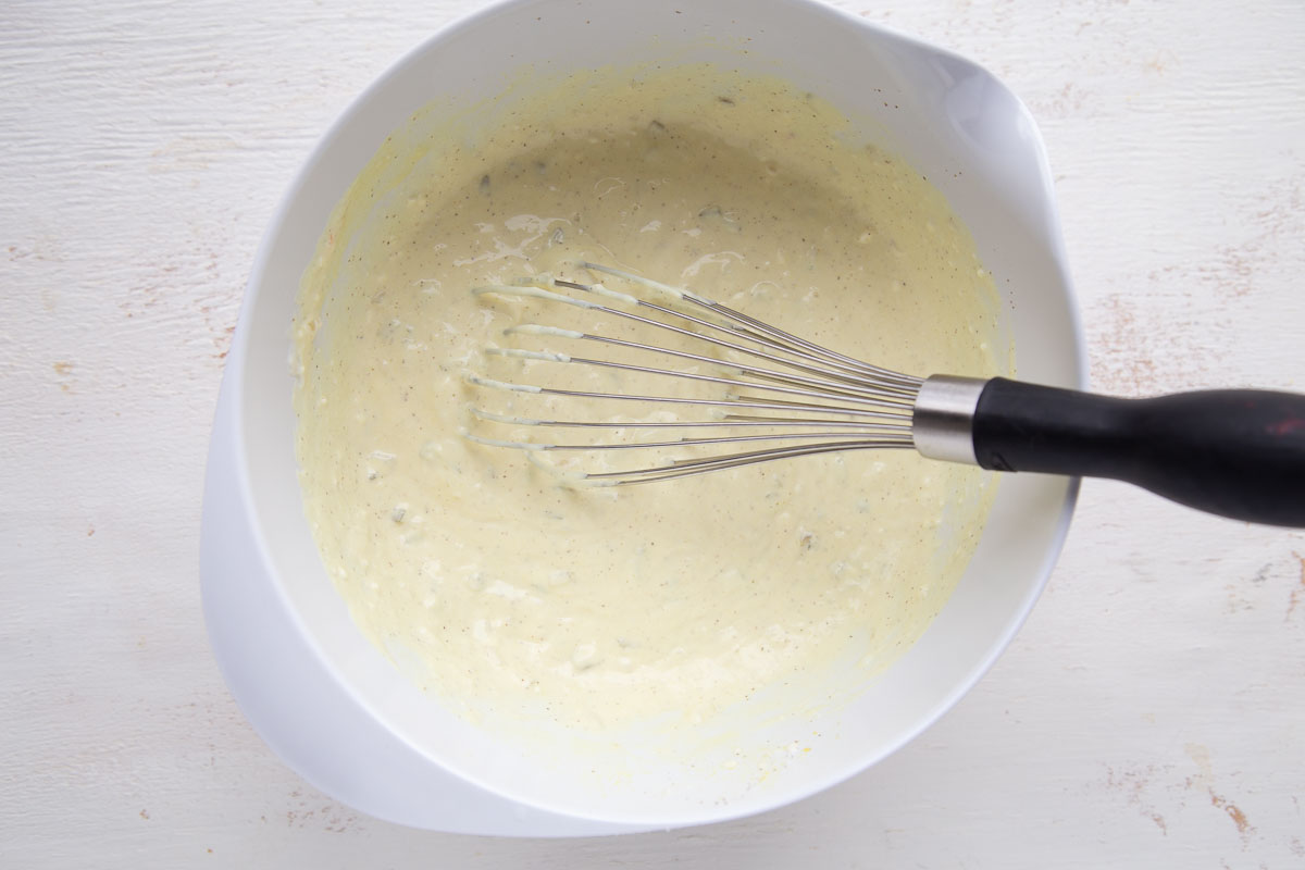 mayonnaise dressing in a white bowl with a whisk.
