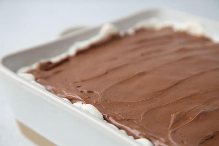 chocolate frosting on top of a marshmallow layer in a cake dish.