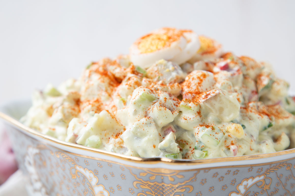 red potato salad in a silver and white bowl.