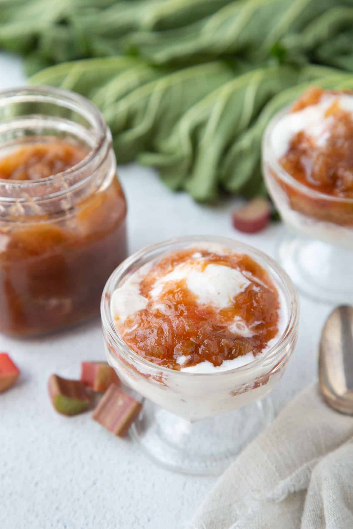 rhubarb sauce in a jar next to parfait glasses with ice cream and rhubarb sauce.