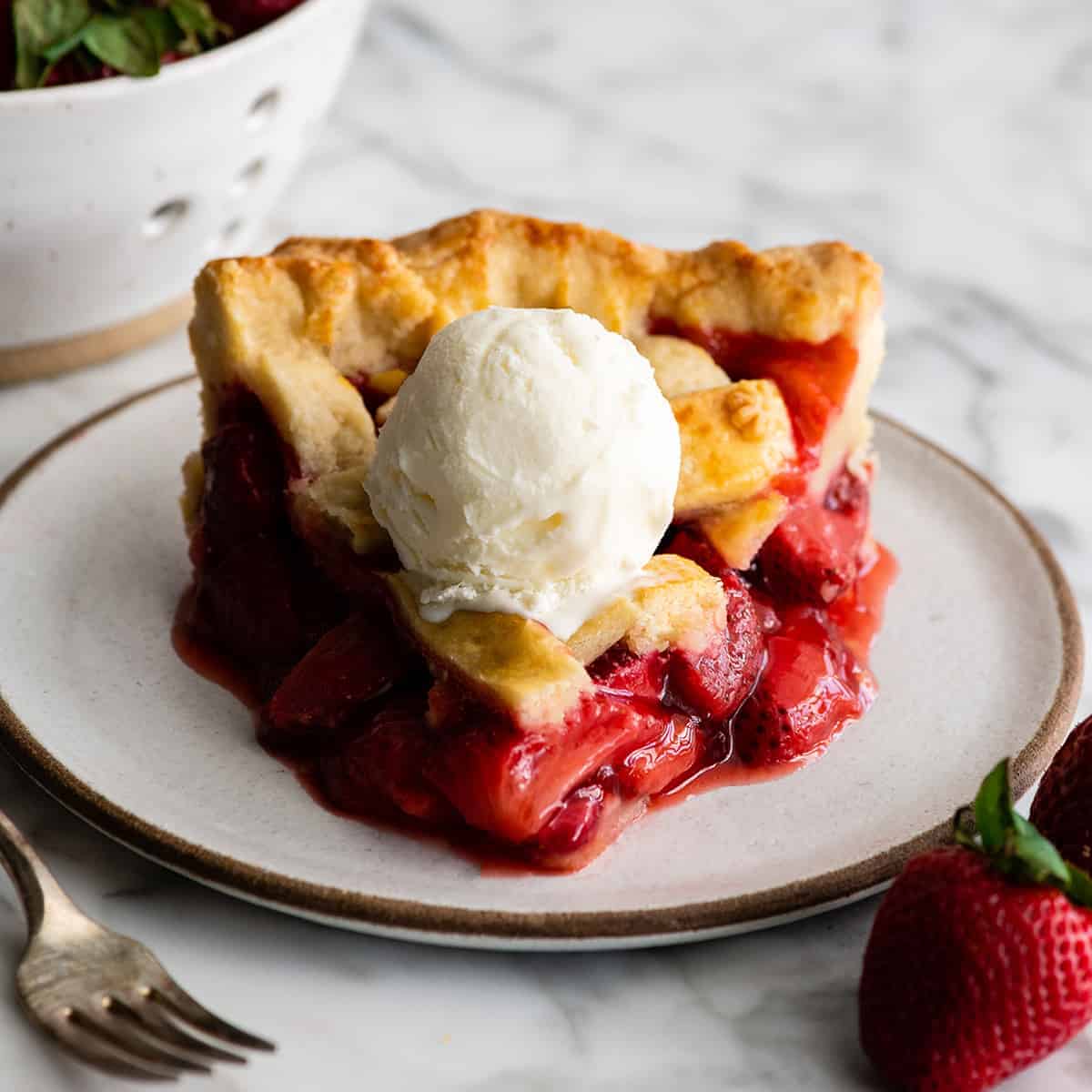 slice of strawberry pie topped with a scoop of vanilla ice cream.