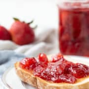 strawberry preserves on toast next to a jar of preserves.