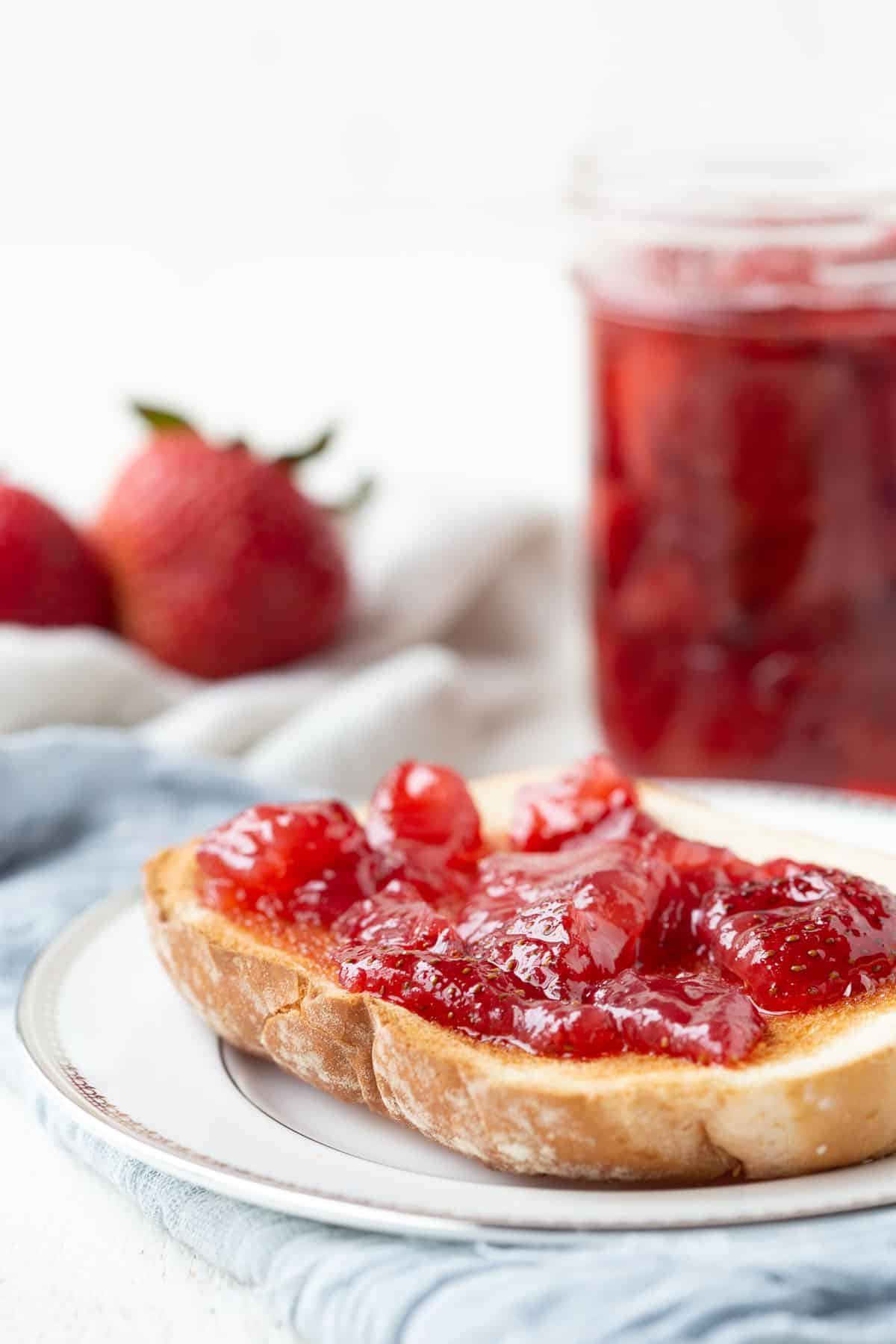 strawberry preserves on toast next to a jar of preserves.