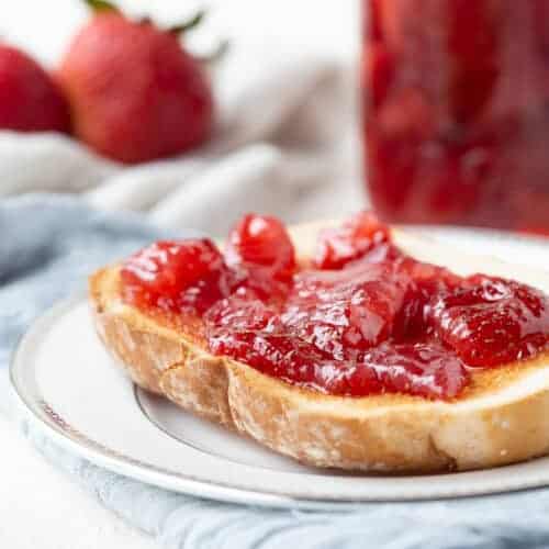 strawberry preserves on toast on a white plate.