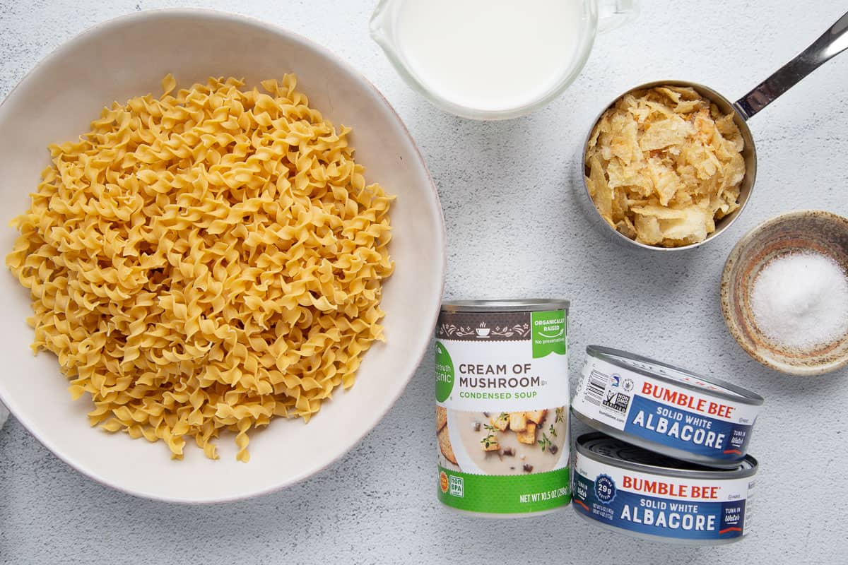 egg noodles, tuna, mushroom soup, and other ingredients on a white table.