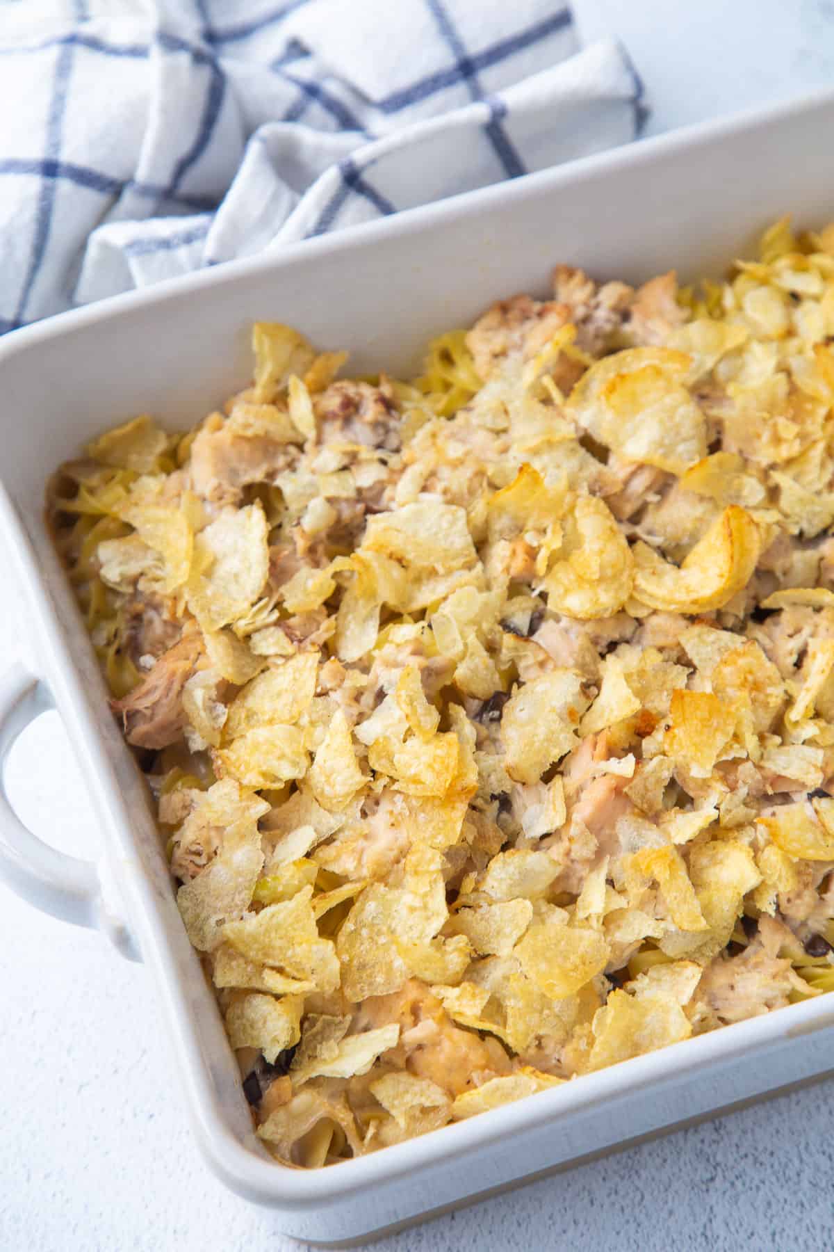 tuna noodle casserole topped with potato chips in a white casserole dish.