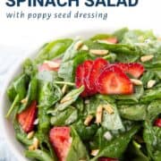 strawberry spinach salad in a low white bowl.