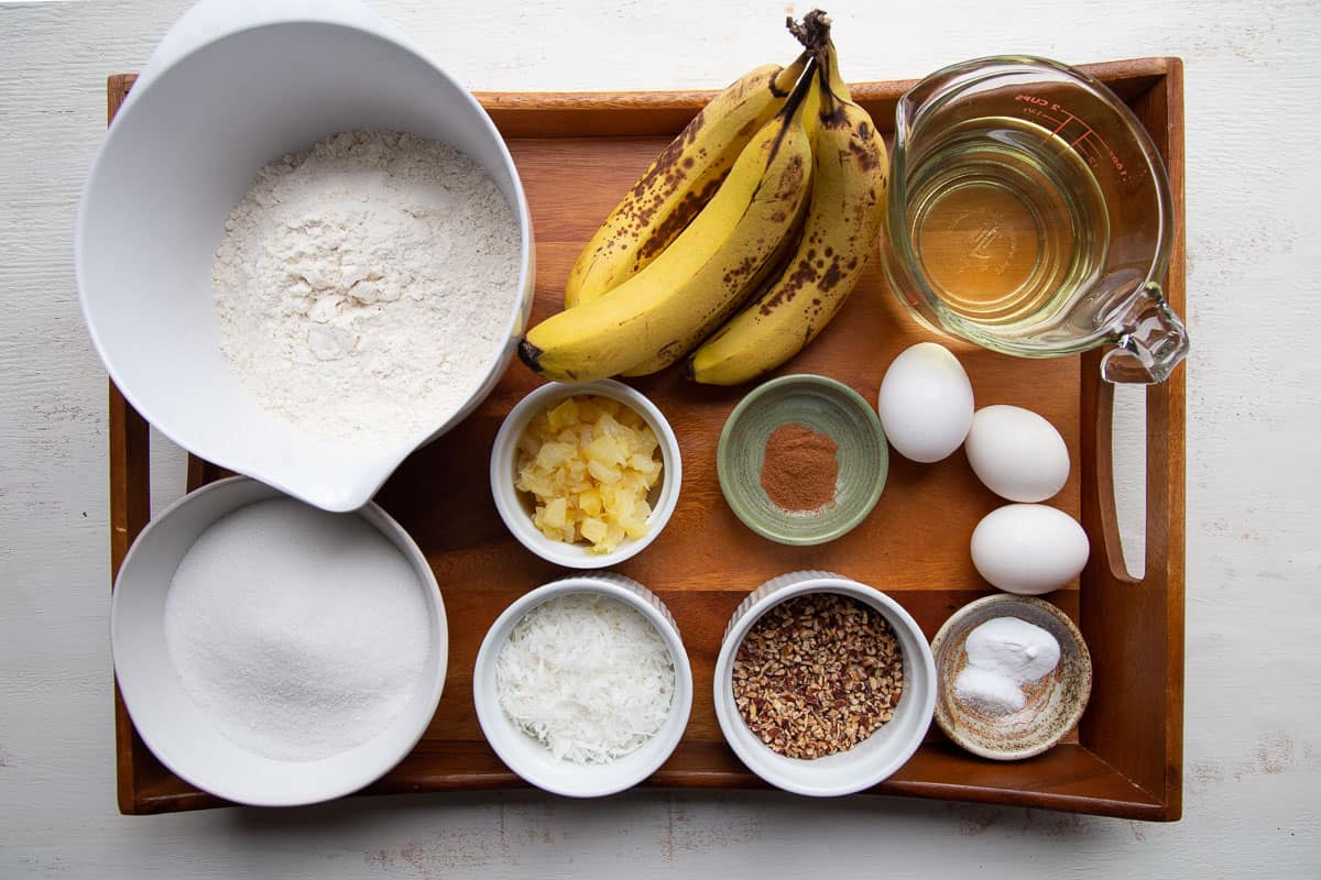 bananas, pineapple, pecans, flour, and other ingredients on a wooden serving tray.