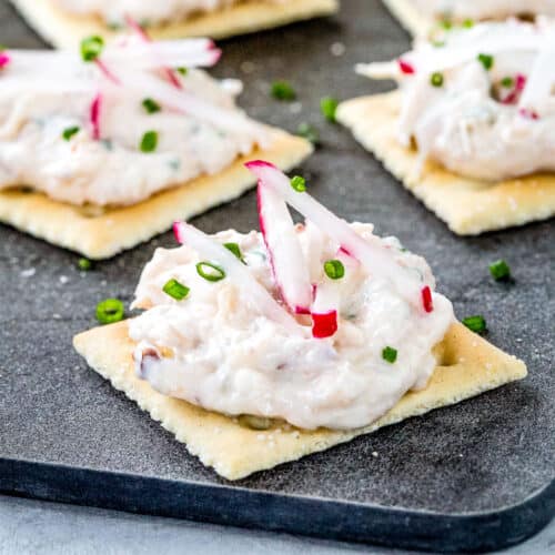 crab dip on saltine crackers on a black board