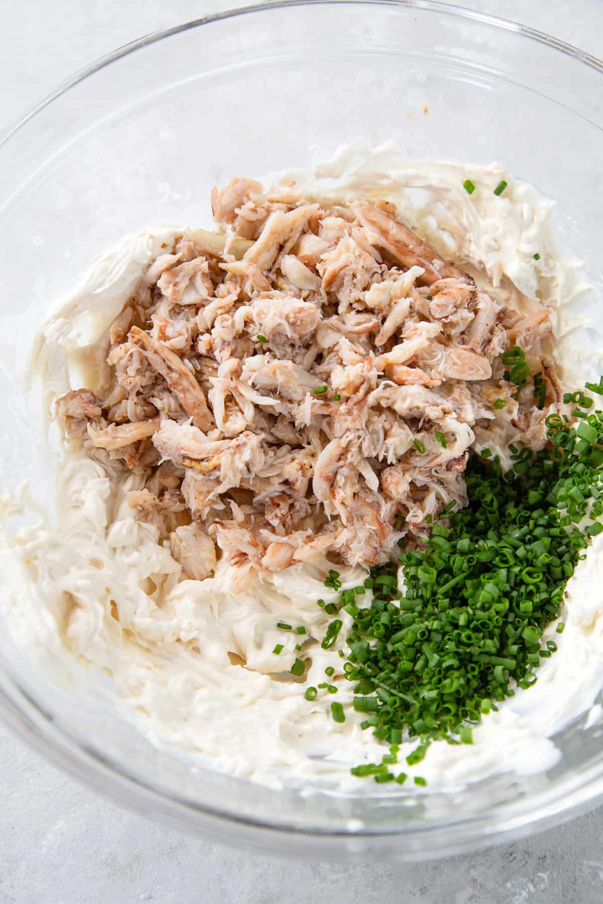 crab dip, chives, and cream cheese in a large glass bowl.