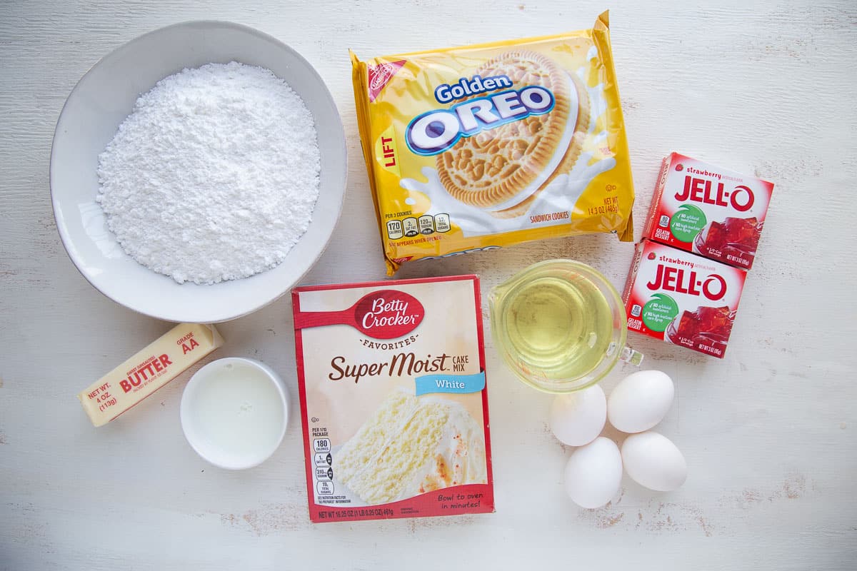 cake mix, golden oreos, strawberry jello, and other ingredients on a white table.