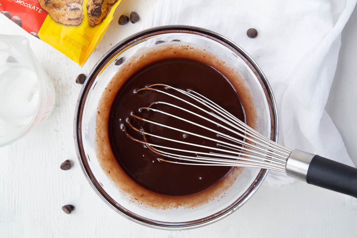whisk in a glass bowl filled with just cooked hot fudge sauce.