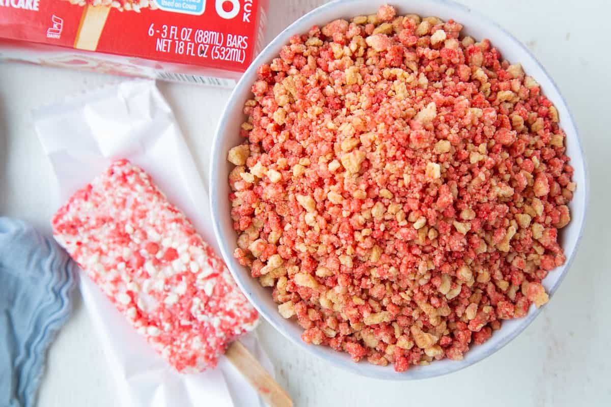 bowl of strawberry shortcake crumble next to a strawberry shortcake ice cream bar.