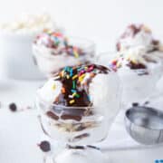 hot fudge sundae with sprinkles in a glass parfait dish.
