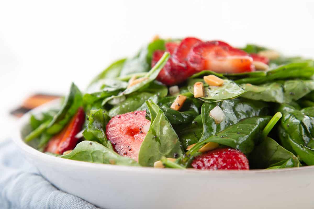 strawberry spinach salad in a low white bowl.