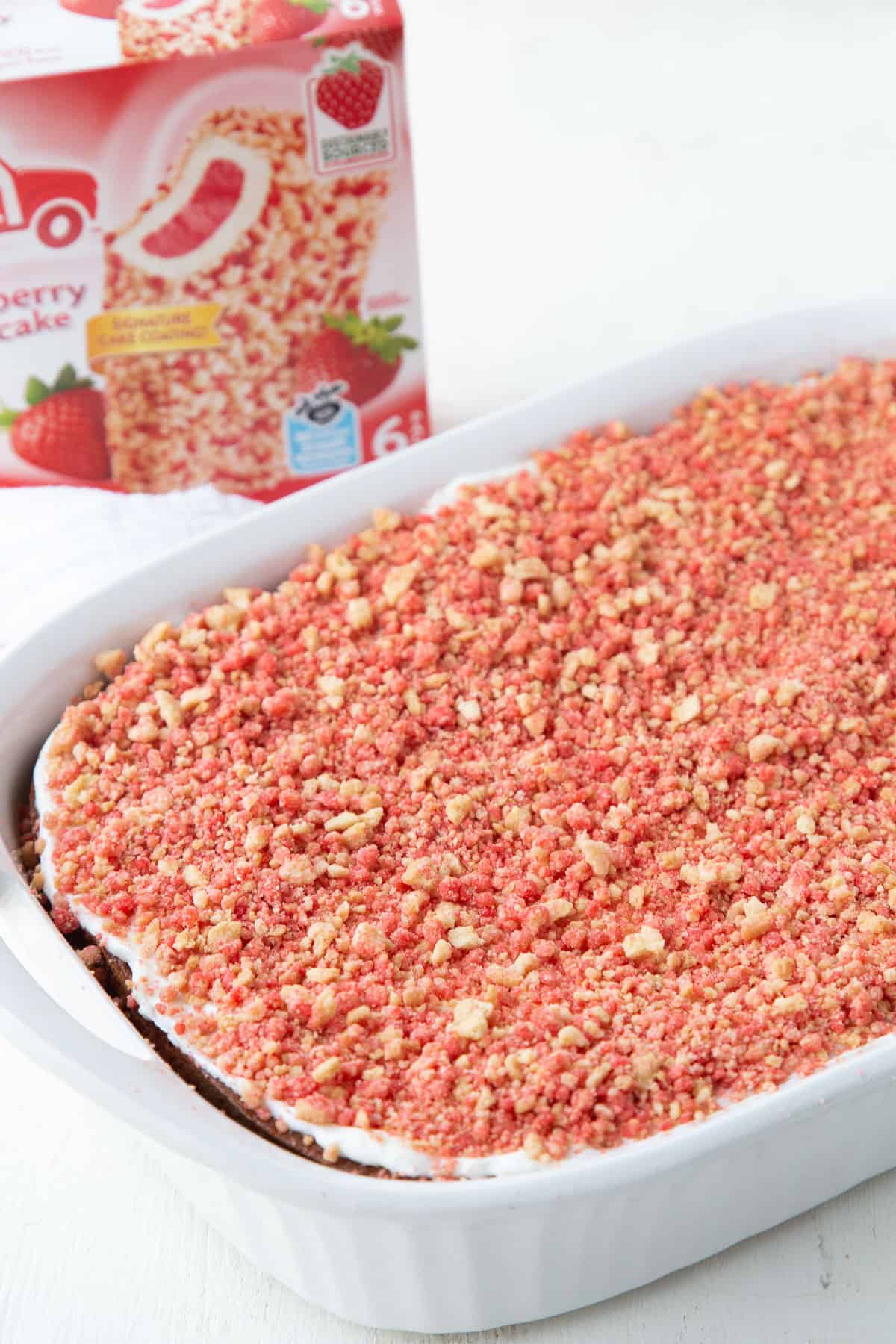 strawberry crunch cake in a white cake pan next to a box of strawberry shortcake ice cream bars.