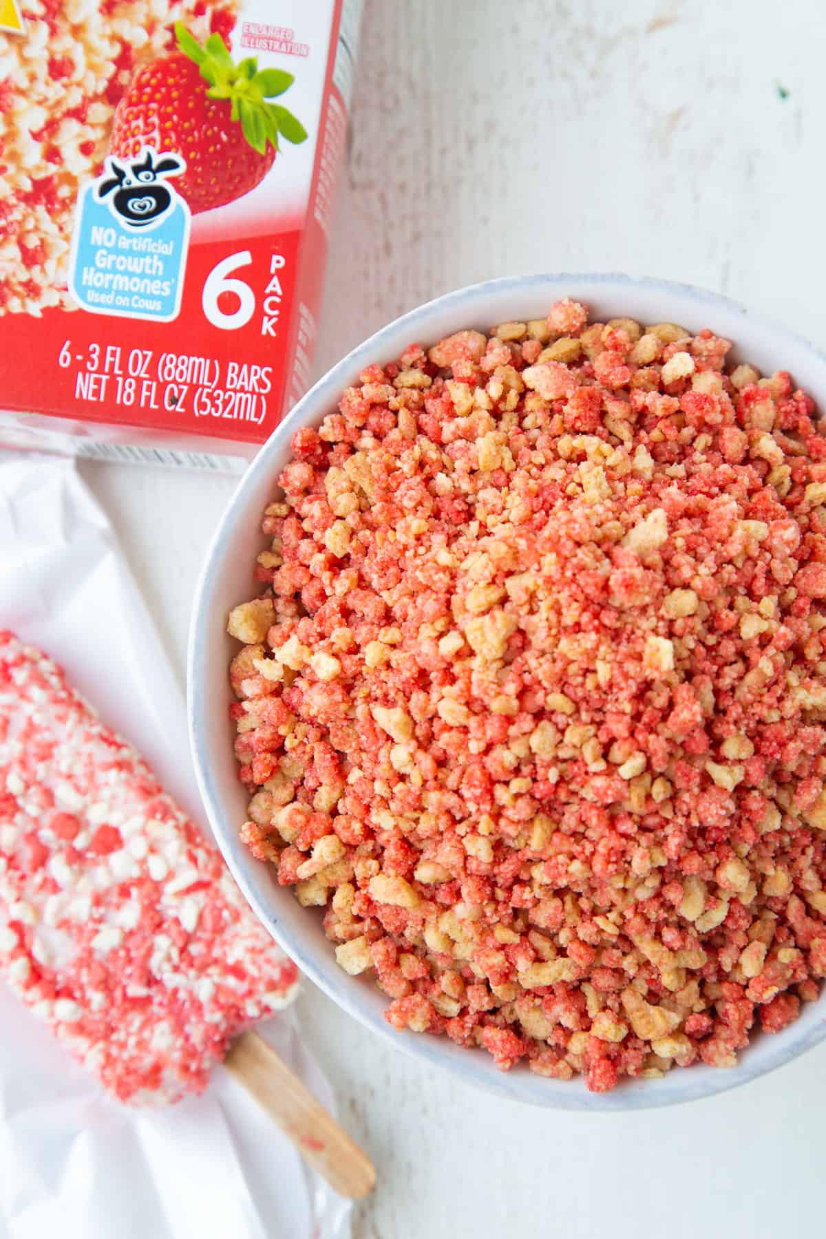 bowl of strawberry crunch next to a box of strawberry shortcake ice cream bars.