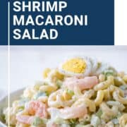macaroni salad topped with shrimp and hard boiled eggs in a white bowl.