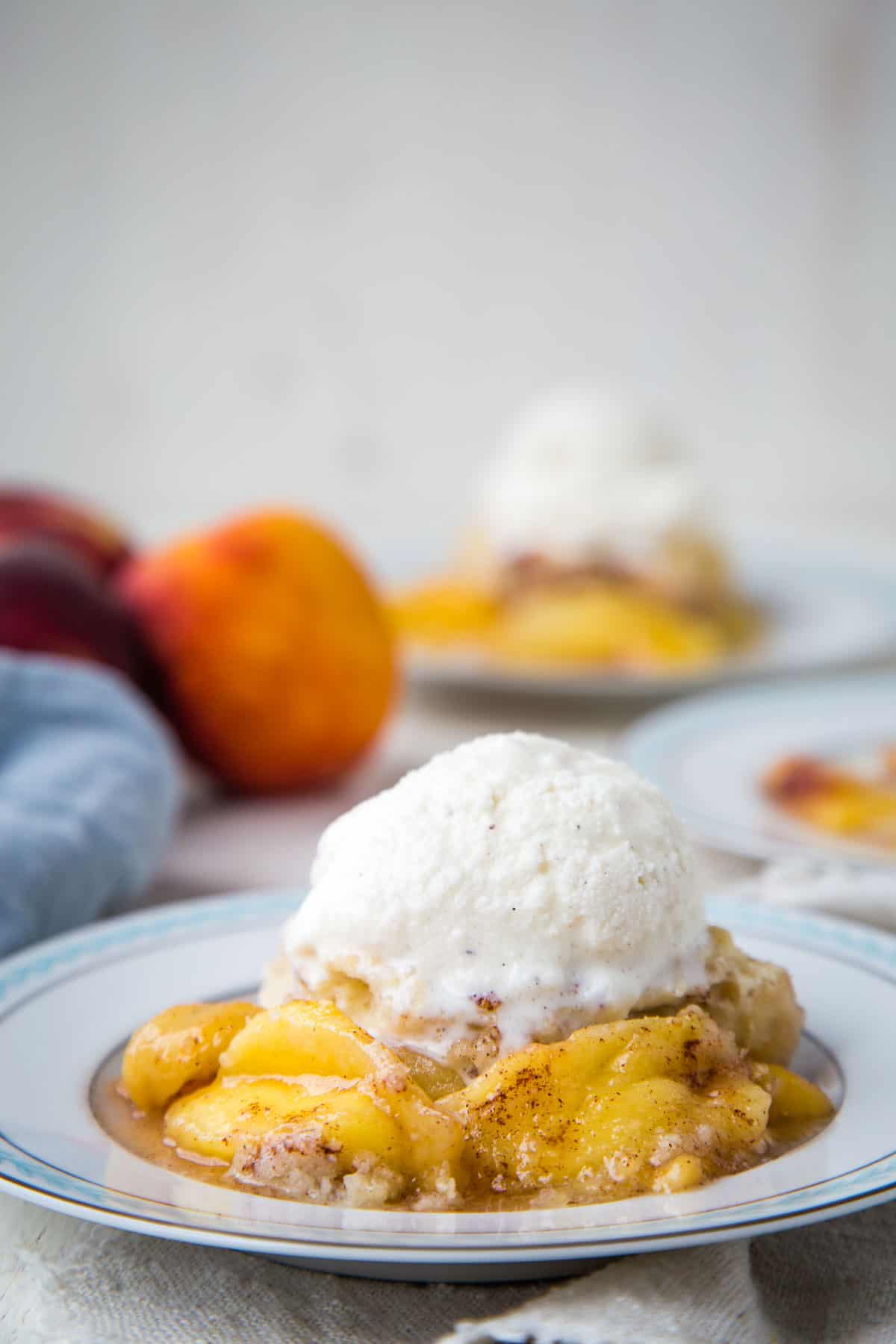 bisquick peach cobbler on a plate topped with vanilla ice cream.