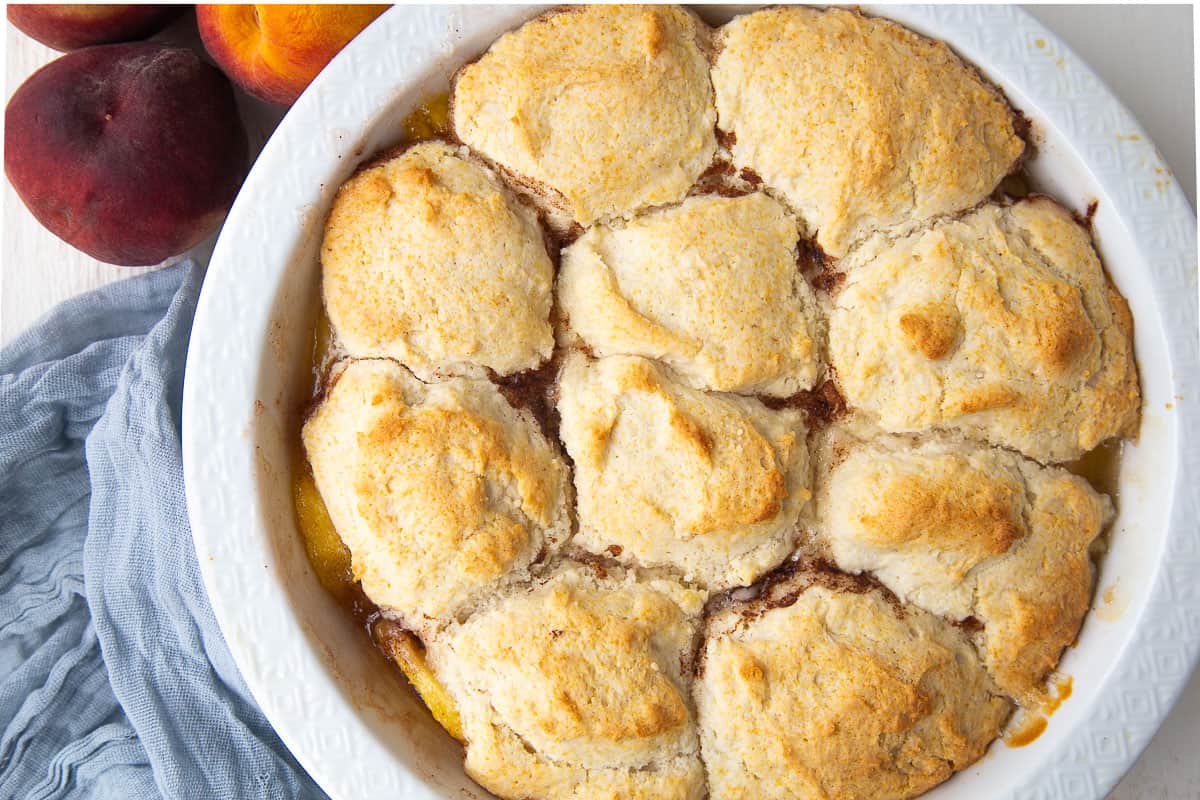 bisquick peach cobbler in a white circular dish.