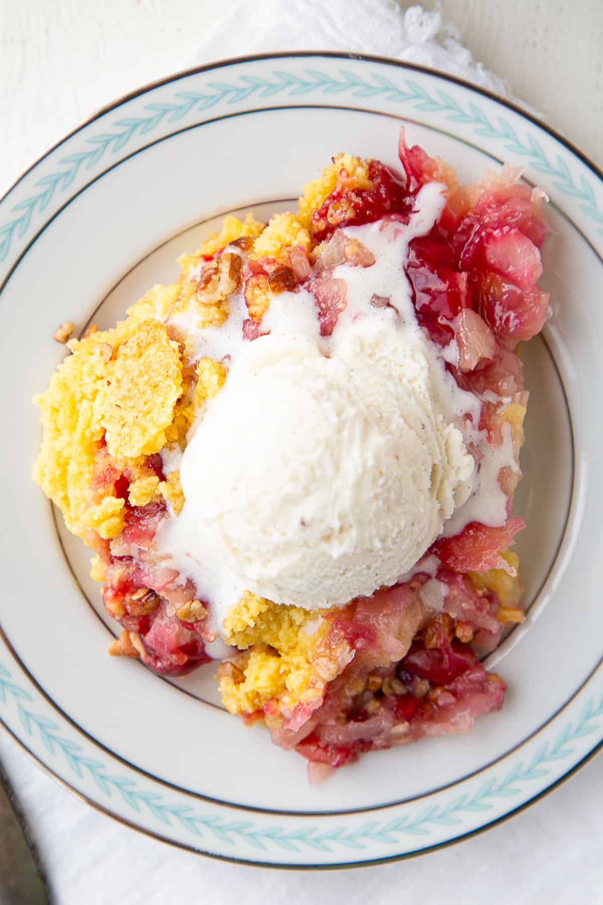 slice of cherry dump cake with pineapple topped with ice cream.