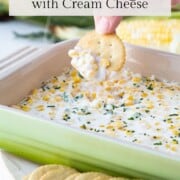 hand scooping up corn dip with a cracker.
