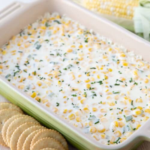 cream cheese corn dip topped with chives in a rectangular baking dish.