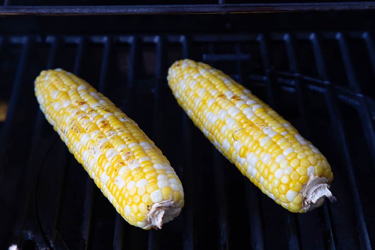 two ears of corn on the grill.