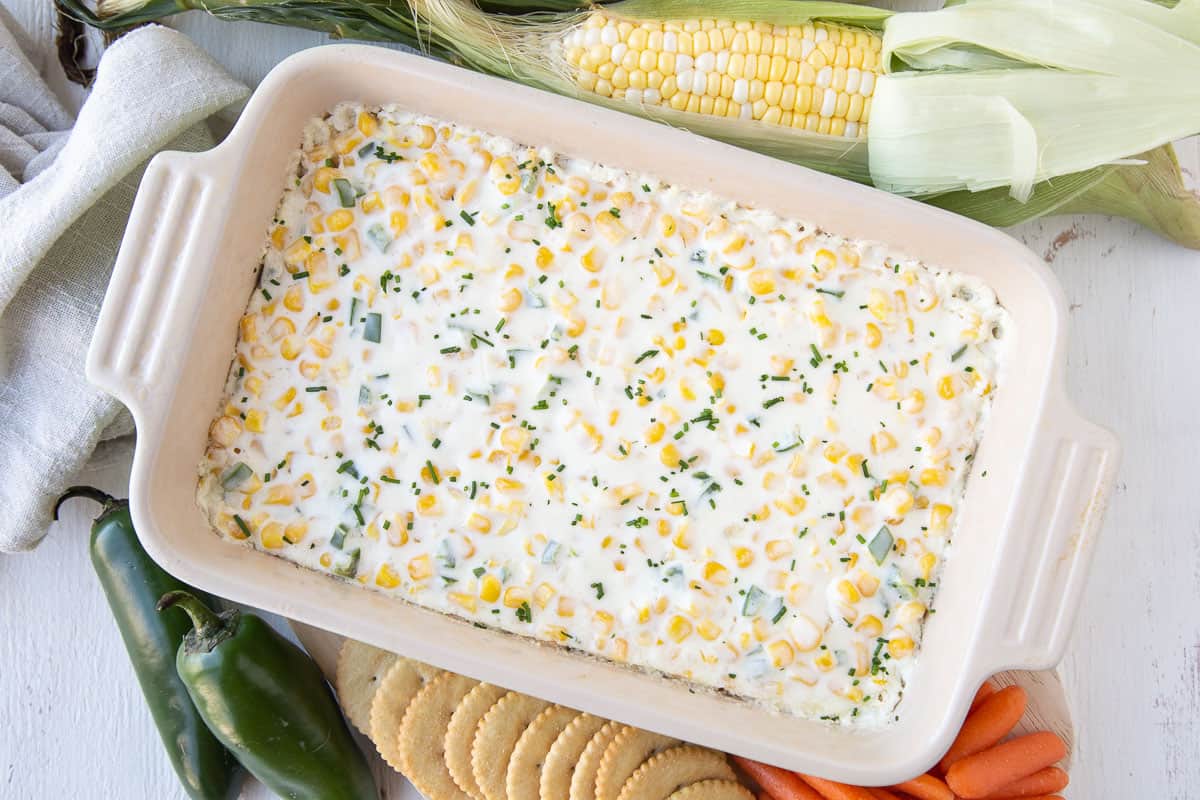 corn dip surrounded by carrots and crackers.