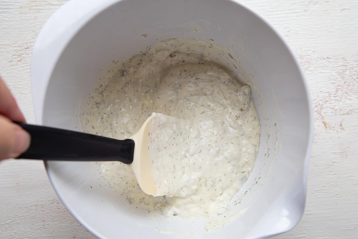 mayonnaise dressing in a white bowl with a spatula.