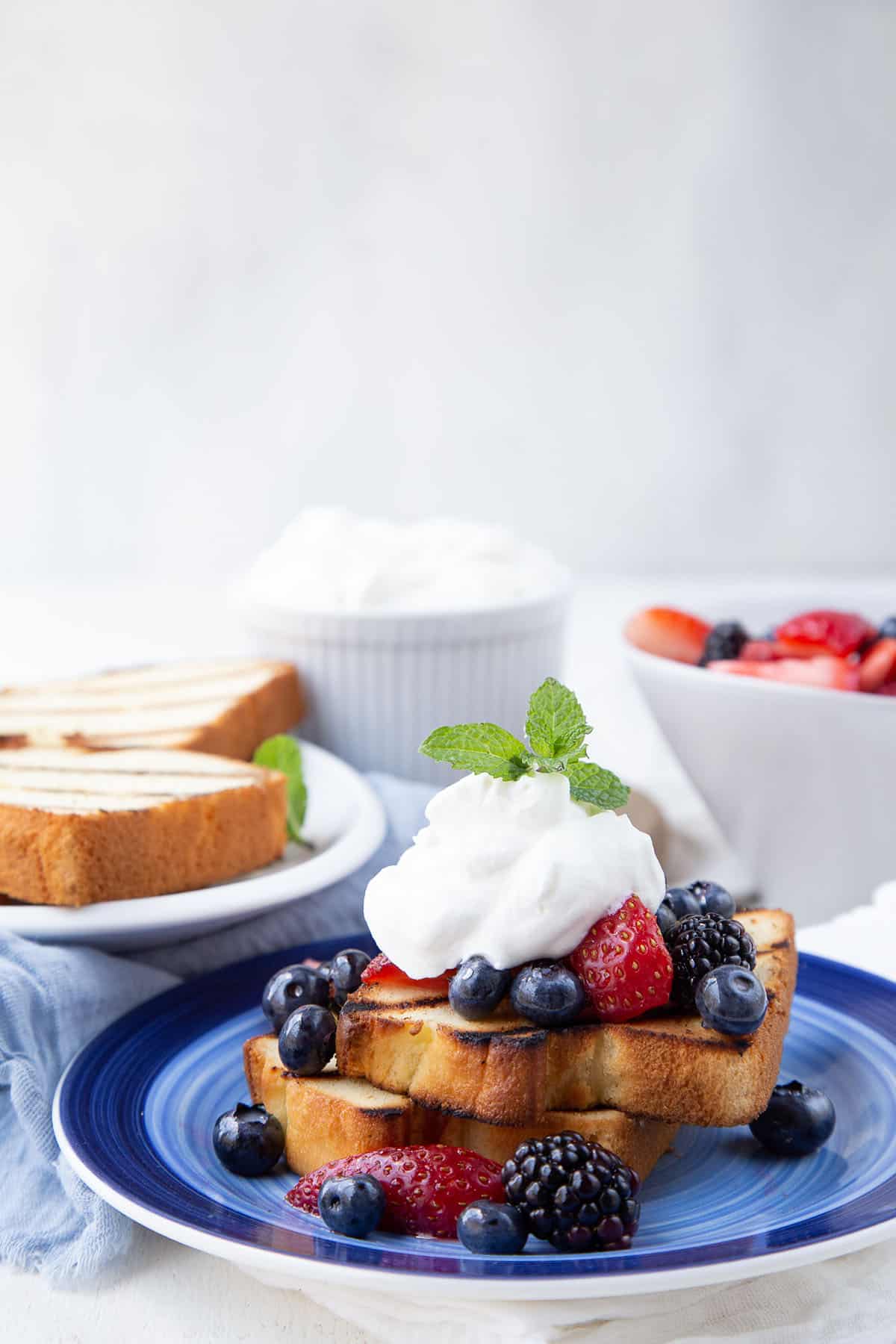 grilled pound cake with berries and whipped cream on a blue plate.