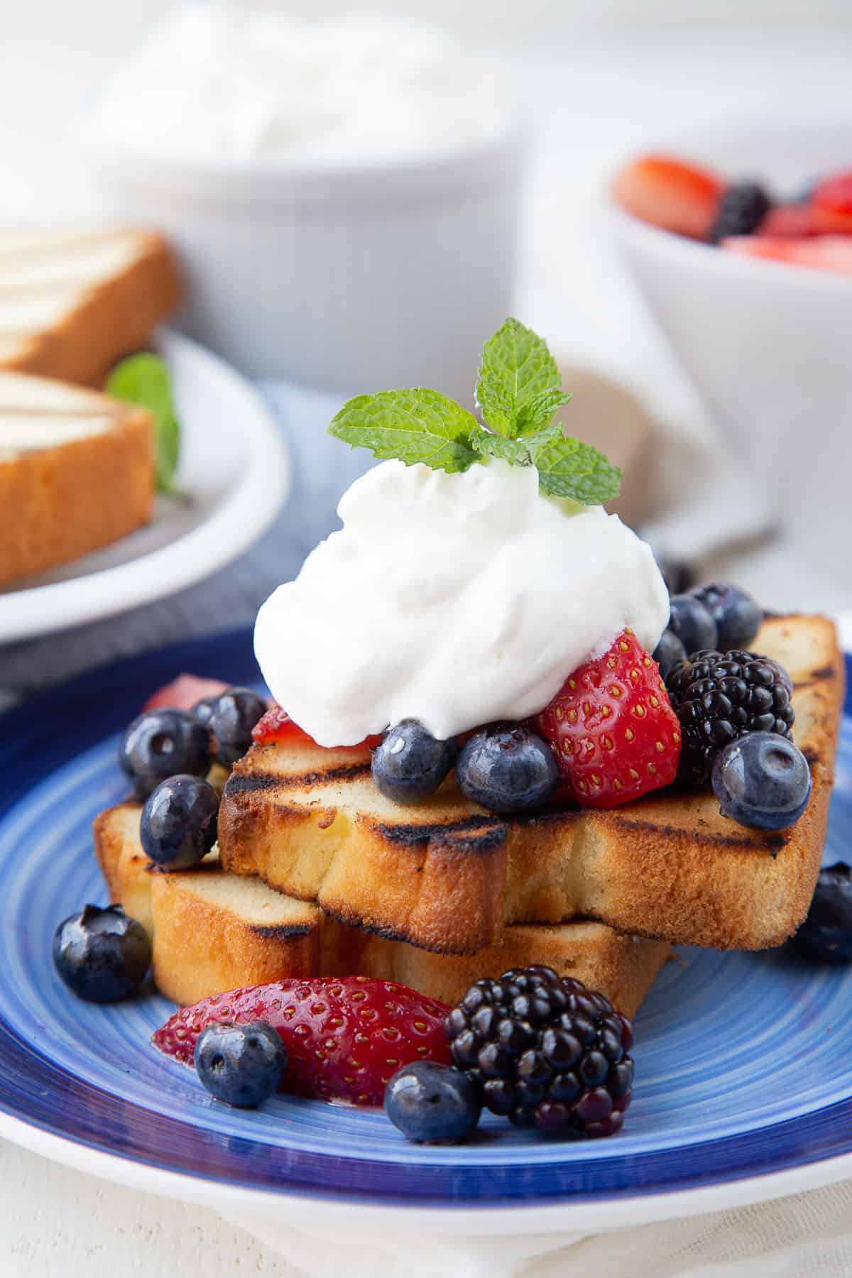 grilled pound cake slices topped with berries and whipped cream.