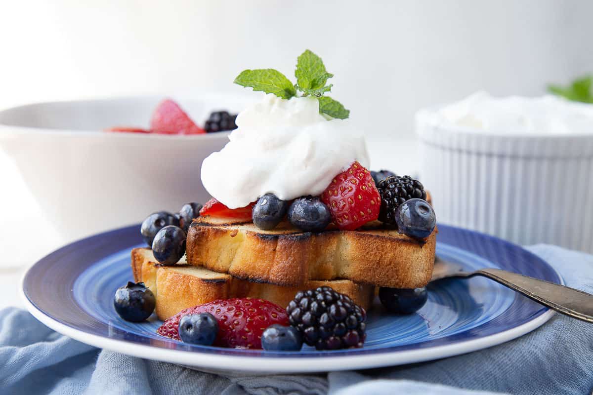 slices of grilled pound cake topped with berries and whipped cream.