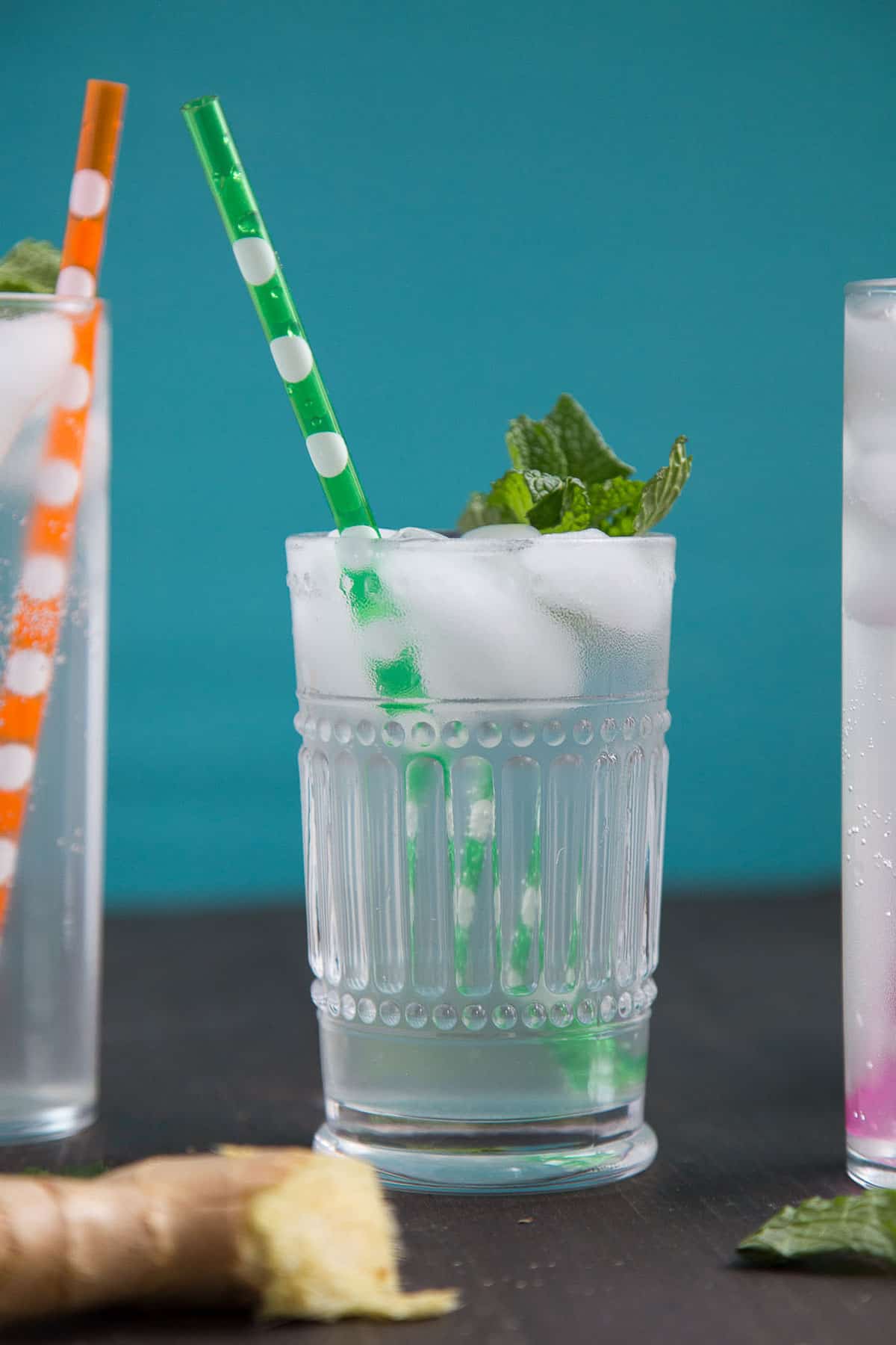 glass of ginger ale with a green polka dot straw, with ice and fresh mint.