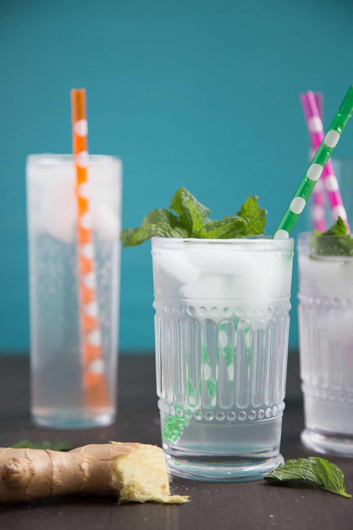 homemade ginger ale in tall glasses with colorful straws and fresh mint garnish.