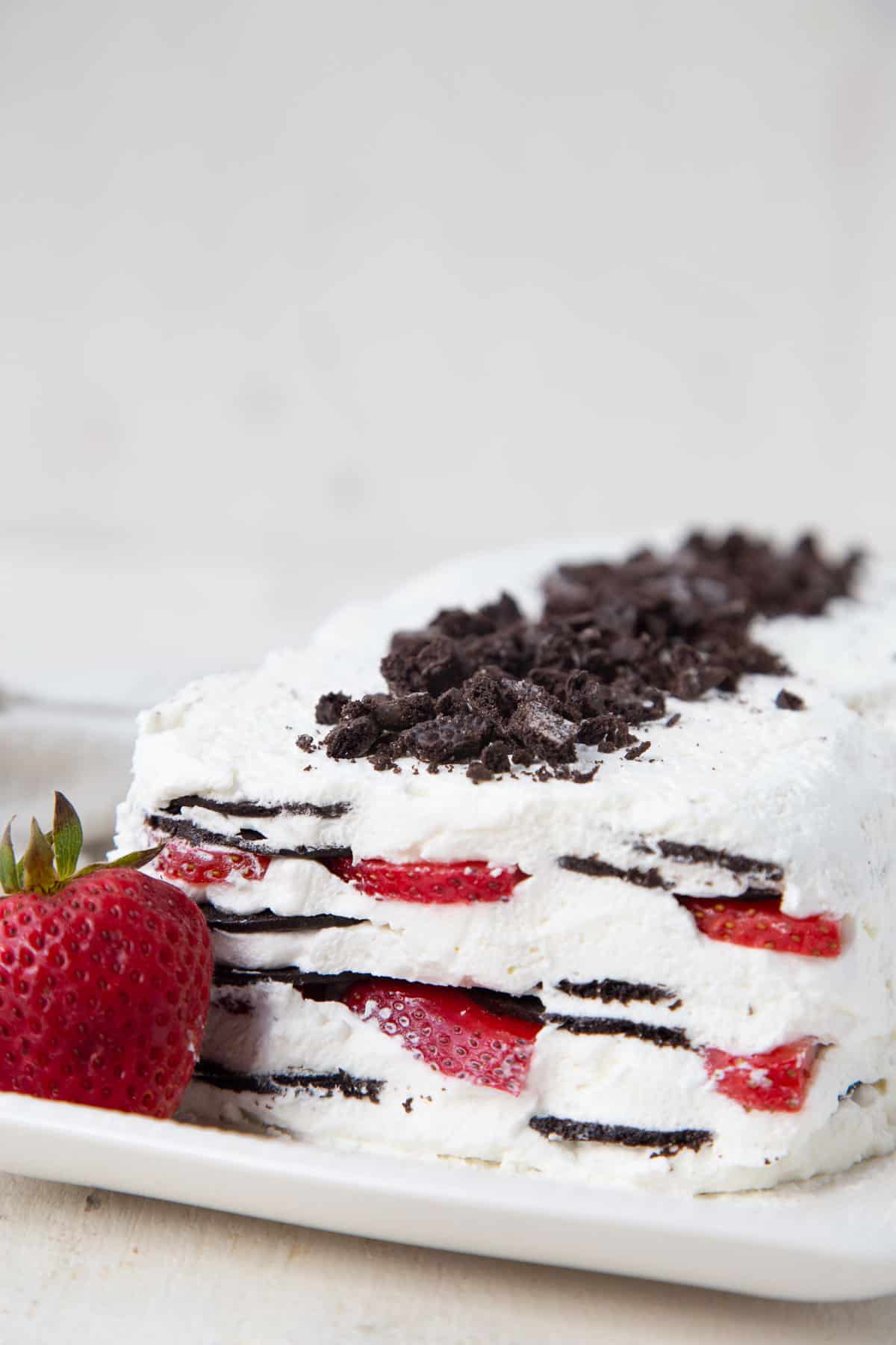 strawberry icebox cake on a white platter with a whole strawberry.