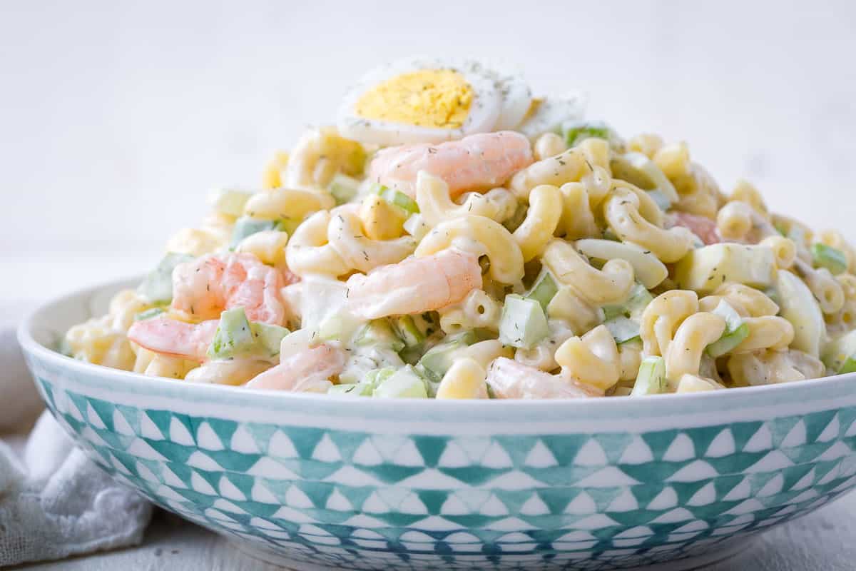 green and white bowl filled with macaroni salad with shrimp.