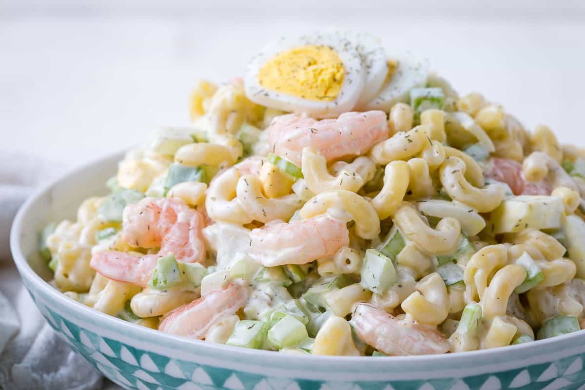 green and white bowl filled with pasta salad with shrimp.