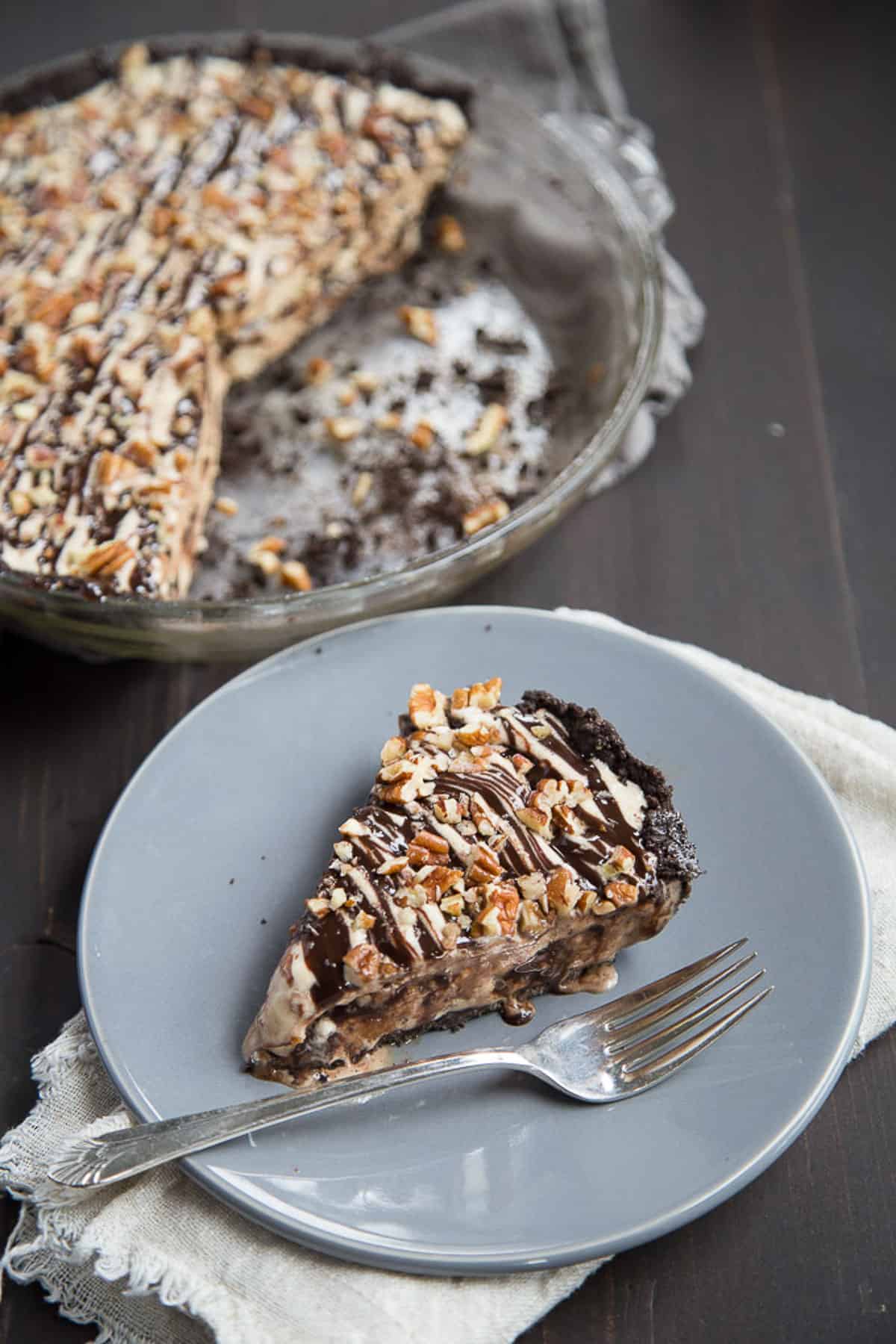 slice of mississippi mud ice cream pie on gray plate next to a whole pie.