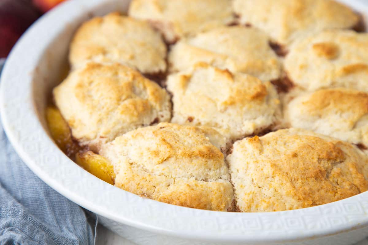 bisquick peach cobbler in a white round dish.