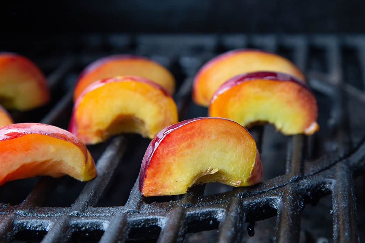 quartered peaches on a grill.
