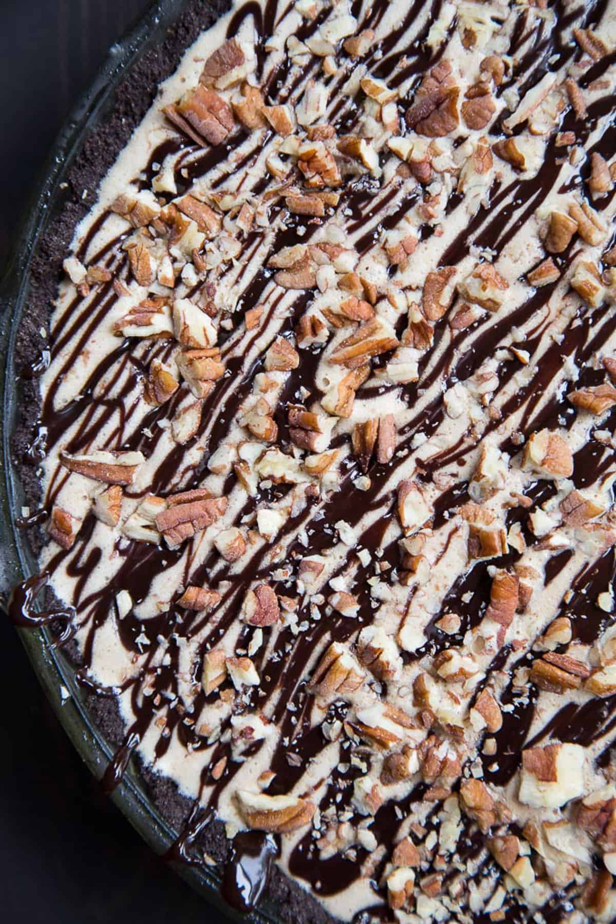 the top of an ice cream pie, with a chocolate drizzle and chopped pecans.